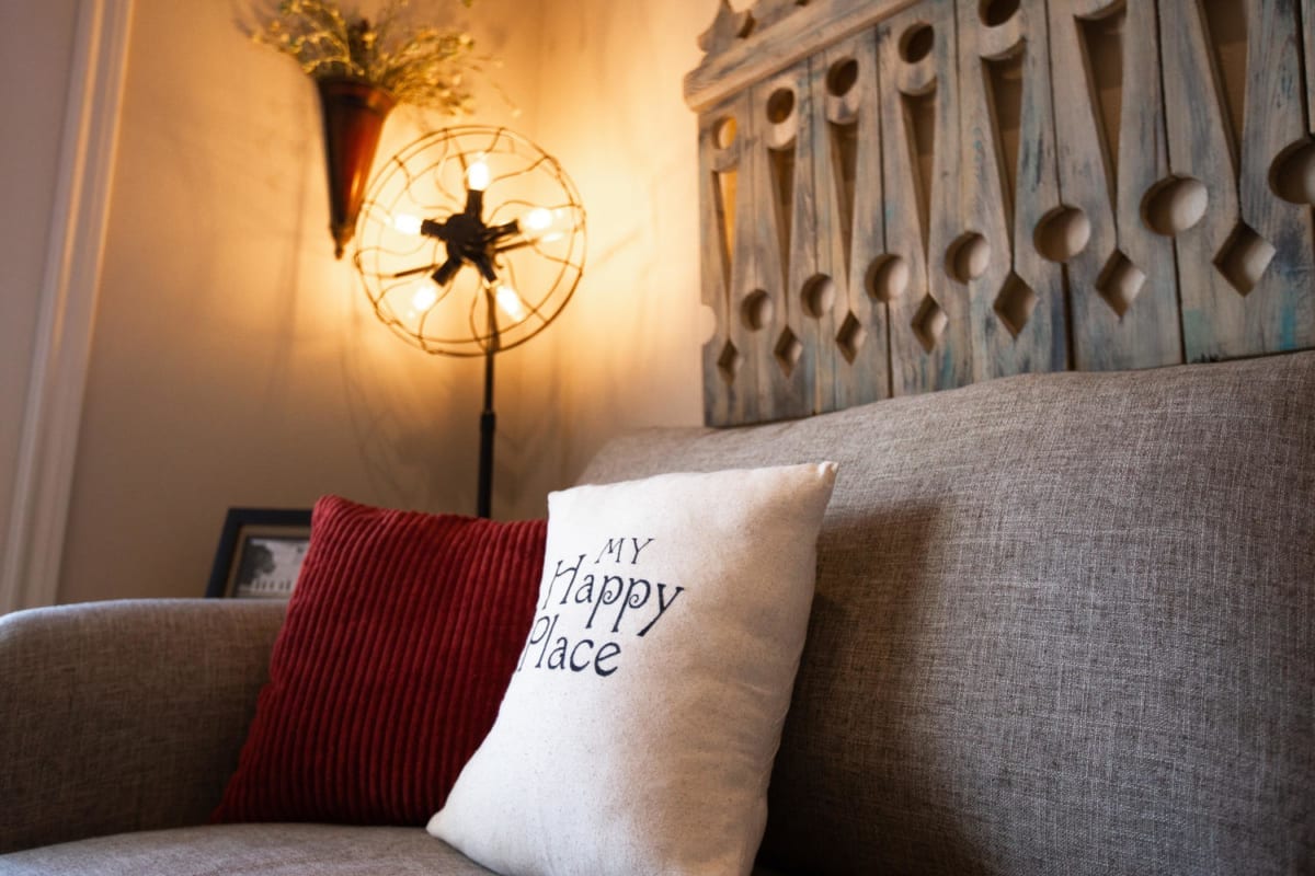 Village at Gruene Condo close up of couch with embroidered pillow. Text: My Happy Place.