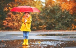 Child in the rain with umbrella.