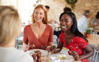 Two women laughing at a brunch meal.